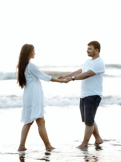 A simple pose of a couple holding hands and walking in the shallow water, showing a calm and connected moment.