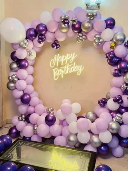 A full balloon ring in shades of purple and silver, set up in a living room.