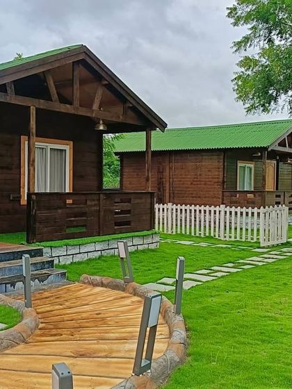 Another angle of the completed farmhouse project, showing the harmony between the wooden cabins, the green lawn, and the custom-designed walkways.