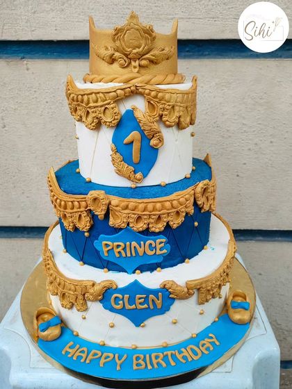 Grand birthdays call for grander cakes. This ornate three-tier prince-themed cake in royal blue and gold is perfect for a majestic first birthday celebration.