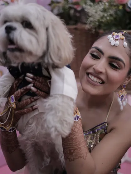 A heartwarming moment between the bride and her furry friend, with her practical and pretty Mehendi braid keeping her hair tidy.
