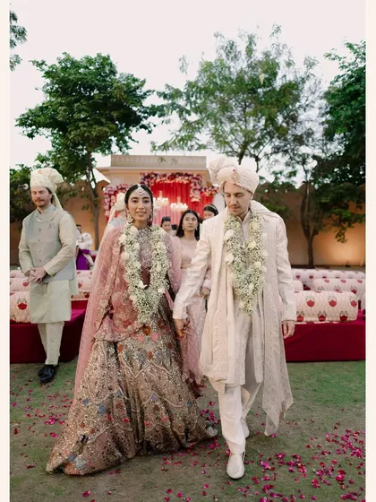 The couple walks hand-in-hand after their ceremony, surrounded by family and the lush greenery of the palace gardens.