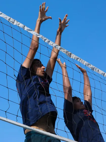 Two players jump in unison to practice a double block. This drill teaches timing, communication, and the importance of creating an impenetrable barrier for the opposing spiker.