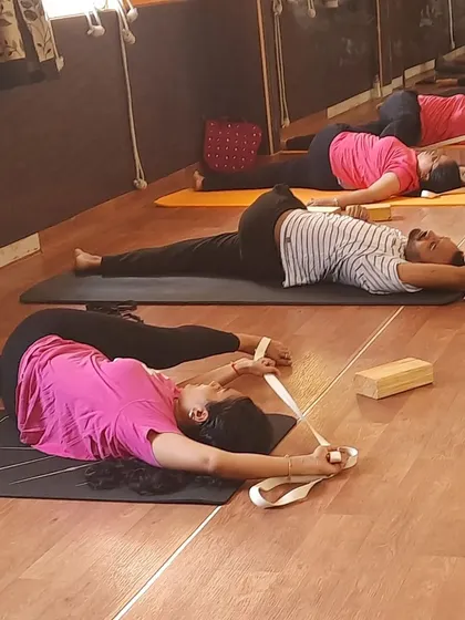 Students using yoga straps for Supta Padangusthasana (Reclining Hand-to-Big-Toe Pose). This is a fantastic way to safely stretch the hamstrings and open the hips without straining the lower back.