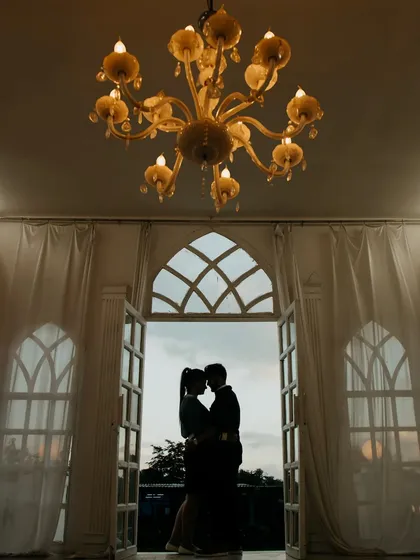 A classic silhouette against an open doorway at dusk. Framed by the elegant architecture and a grand chandelier, this shot is the epitome of timeless romance and sophistication.