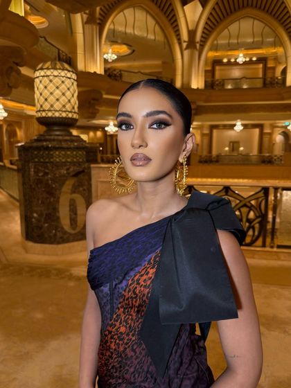 A high-fashion moment in a Schiaparelli gown. The makeup is sculpted and defined, with a strong focus on the eyes to match the avant-garde outfit.