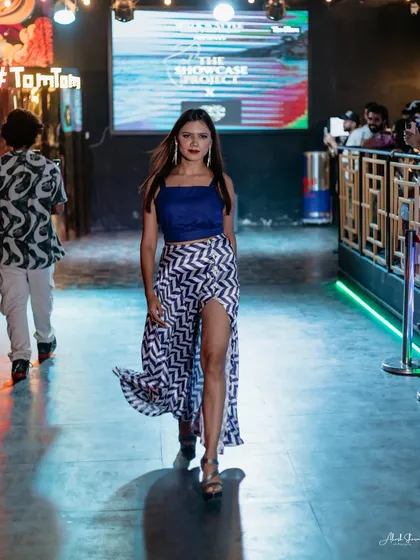 A model walks the runway at TomTom Skybar in a stylish blue crop top and a high-slit patterned skirt, capturing a chic, contemporary look.