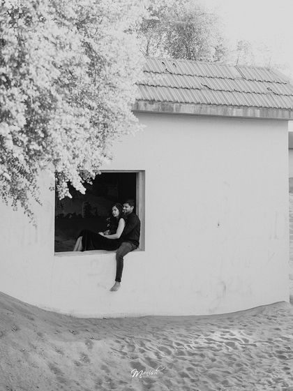 A striking black and white shot of the couple sitting in a window, the contrast creating a powerful and artistic pre-wedding portrait.