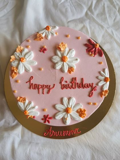 Simple is aesthetic. This pretty pink birthday cake is decorated with hand-piped daisies in warm, rustic colours for a charming and sweet look.