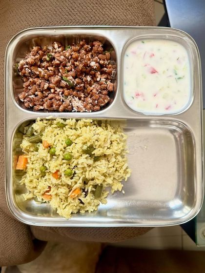 A balanced meal of vegetable pulav with a side of horse gram sundal and raita.