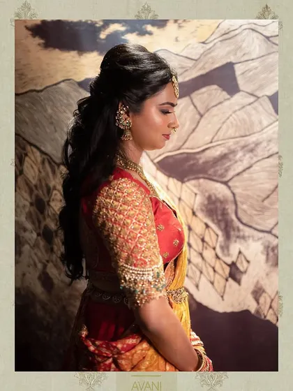 A side profile of a bride, highlighting the detailed embroidery on the sleeve of her red blouse. The intricate patterns are a key feature of my bespoke bridal wear.