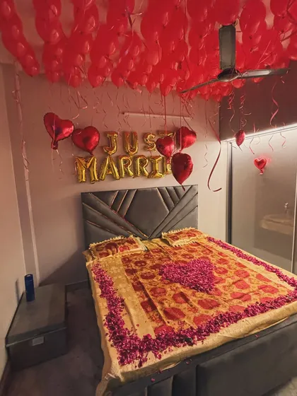 A classic 'Just Married' room decoration to welcome the newlywed couple. The ceiling is filled with red balloons, with gold foil 'Just Married' balloons on the wall. We also decorated the bed with a heart shape made from fresh rose petals for a special romantic touch.