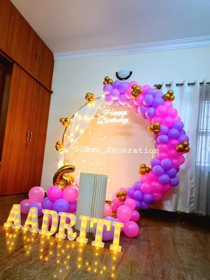 A similar setup for a 6th birthday, using a purple and pink balloon ring and the name 'Aadriti' in marquee letters.