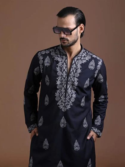 This dark navy kurta features extensive, intricate white embroidery around the neckline and scattered motifs. It's a statement piece that blends traditional artistry with a bold, modern aesthetic.