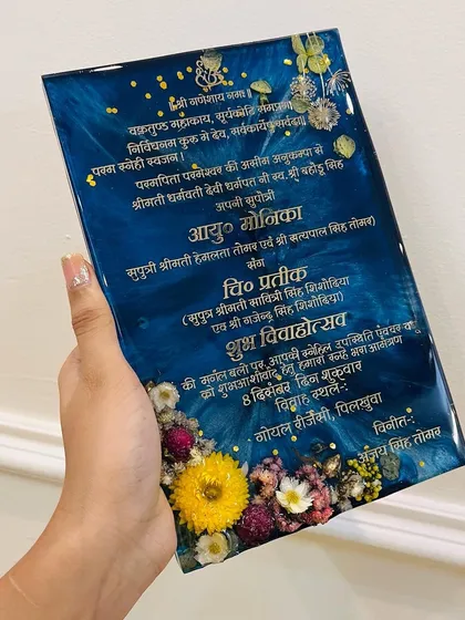 This is a close up of one of my classic resin wedding invitations. The deep blue resin background makes the gold lettering pop, and I embedded real, colorful dried flowers along the bottom to create a beautiful floral border. The glossy finish gives it a very premium feel.