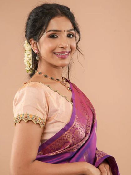 A lovely peach-colored blouse with delicate embroidery on the puff sleeves. This is a feminine and charming design, perfect for daytime events.