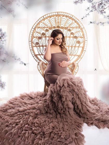 A regal portrait with the client seated on the boho peacock chair, wearing a magnificent dusty mauve ruffled gown. The floral accents add a touch of romance to this stunning setup.
