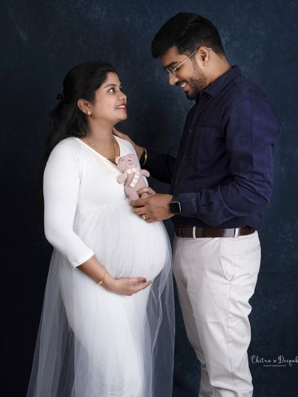 A sweet and playful moment. The partner holds up a teddy bear, a cute prop that adds a touch of fun to the maternity session.