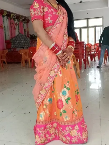 A beautiful client celebrating in a custom-fitted rental lehenga. The vibrant orange and pink floral design is perfect for daytime events like a mehendi ceremony or a festive puja.