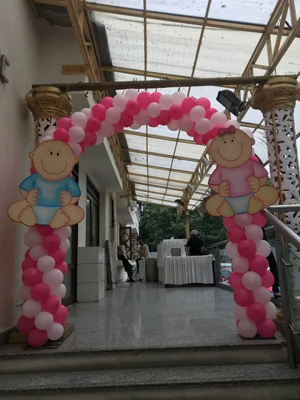 Welcome your guests with a cheerful entrance. This balloon arch uses a pink and white palette with cute baby cutouts, setting a happy mood right from the start.