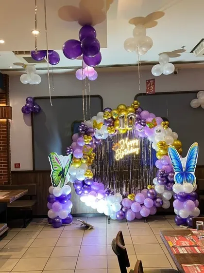 The full restaurant setup for the butterfly-themed 10th birthday, including ceiling balloons and the main photo backdrop.