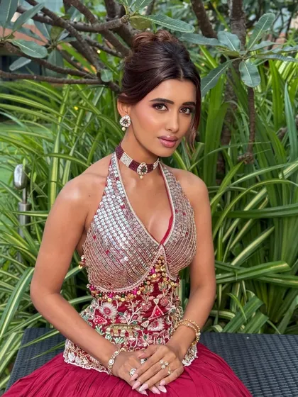 The complete look is a vision that blends tradition with modern glamour. The halter-neck top and choker add a contemporary edge to the festive attire.
