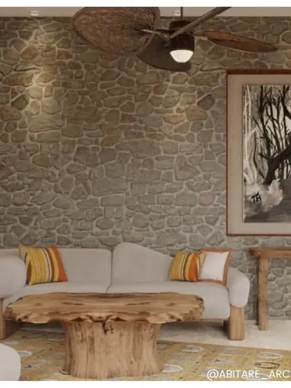 The sitting area in a Dev Villa, showcasing the blend of rustic and modern design. A rough-hewn stone wall is paired with a sleek, contemporary sofa and minimalist furniture.