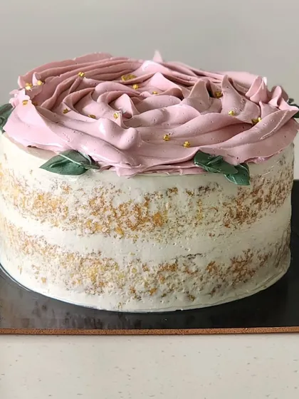 A simple yet elegant vanilla and strawberry cake. This is a semi naked Genoise sponge with layers of light vanilla buttercream and a fresh strawberry filling, decorated with a buttercream rose on top.