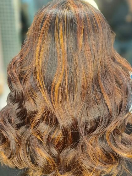 Warm copper and auburn highlights are a fantastic way to add warmth and vibrancy to dark brown or black hair, as seen in this beautifully styled result.