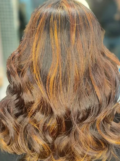 Warm copper and caramel highlights woven through a dark base. This technique adds dimension and a touch of brightness without requiring a full global color service.