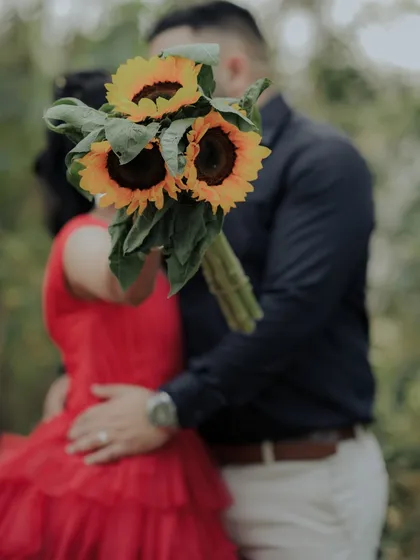 An artistic shot where the couple's embrace is partially hidden by a bouquet of sunflowers. This creative composition focuses on their connection while adding a touch of mystery and romance.