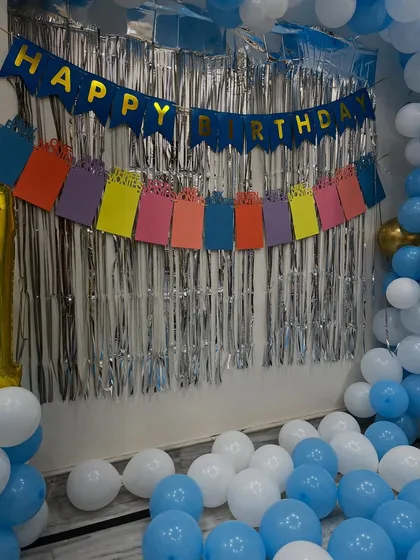 A close-up of the 'Happy Birthday' banner and foil curtain backdrop.