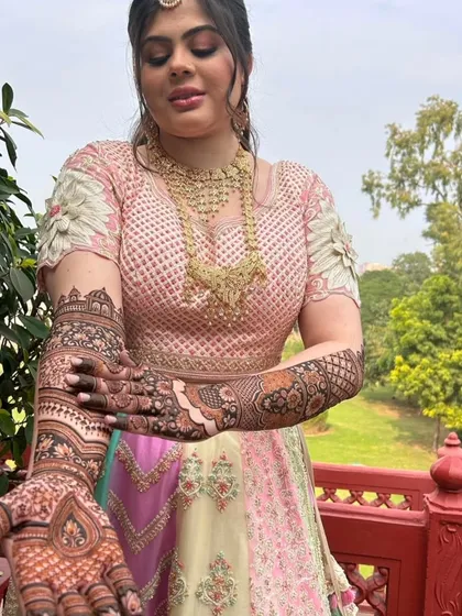 A close-up of the bride showing her palms, which are covered in a dense and intricate traditional design.