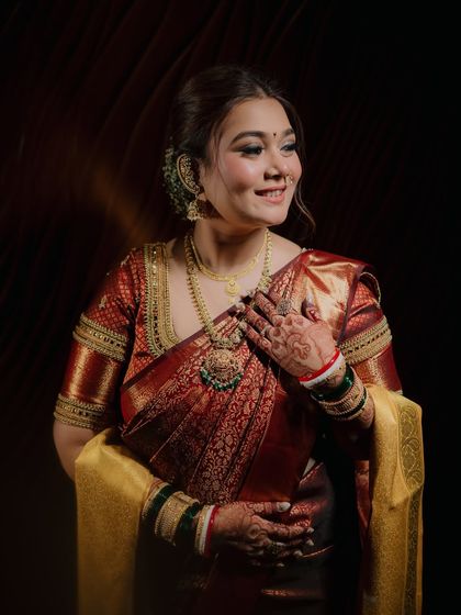 A close-up portrait of the bride, Ekta, her hand to her chest and a happy smile on her face. The lighting perfectly captures the glow of a bride.