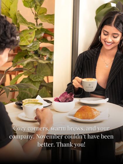 Cozy corners, warm brews, and your company. A couple enjoys a date at our cafe, surrounded by plants and soft light.