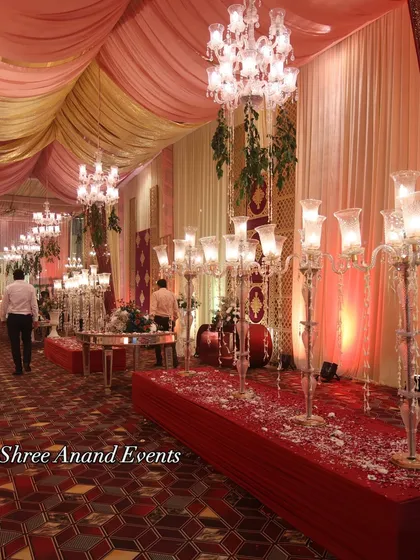 A classic and elegant walkway lined with tall, crystal candelabras and strewn with flower petals, leading guests into the main celebration area.