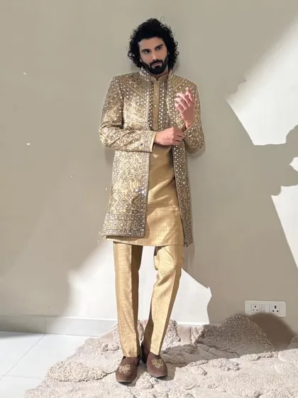 A full shot of a model in a stunning golden sherwani. The grooming here was key to making sure his face looked as regal as the outfit, with clear skin and perfectly styled hair and beard.