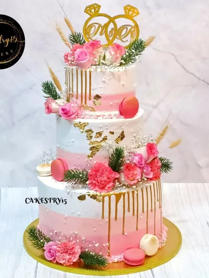 A grand 8kg, three-tier "Just Engaged" cake. This masterpiece is adorned with a lavish display of fresh pink roses, baby's breath, and delicate macarons.