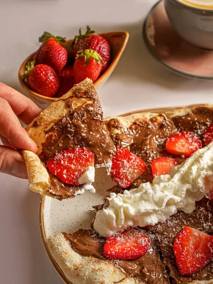 A dessert pizza with Nutella, strawberries, and cream. This shot captures the fun and indulgence of a sweet pizza, perfect for a dessert menu or a special promotion.