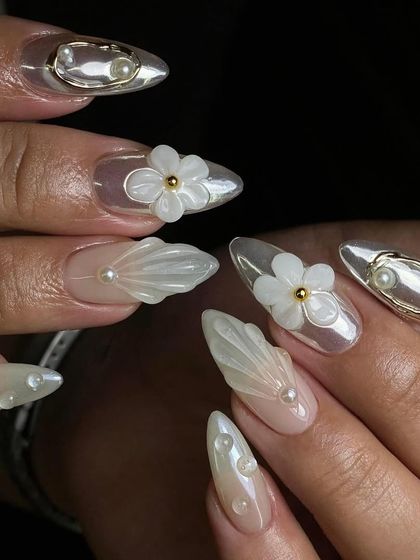 A dreamy, ethereal design. These nails feature a pearlescent base with 3D shell textures, delicate pearls, and sculpted white flowers.