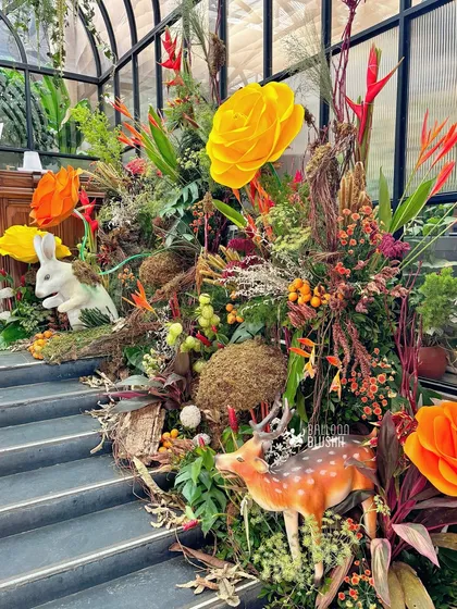 A staircase adorned with woodland creatures, oversized paper flowers, and rich foliage, leading guests into the magical baby shower.