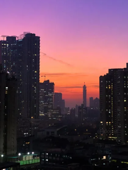 A perfect sunset over Mumbai, with the sky glowing in shades of purple, pink, and orange above the city's buildings.