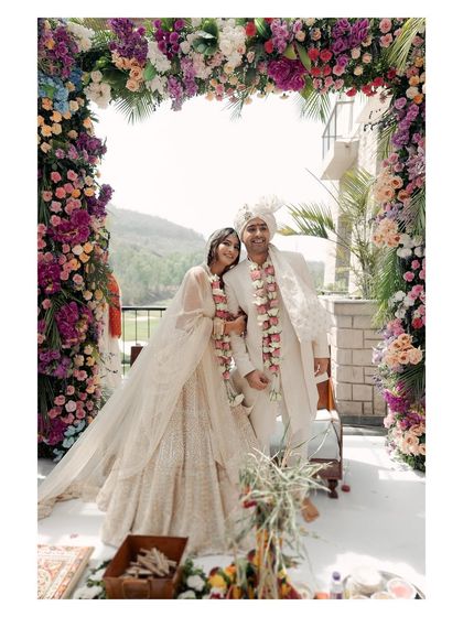 A full view of the wedding mandap, framed by a vibrant floral arch. This image showcases the beautiful decor and the picturesque setting of the Oxford Golf Club wedding.