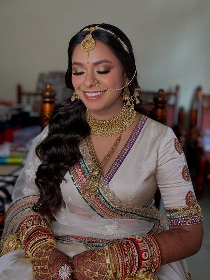 A happy, smiling portrait. The dewy finish on her skin catches the light beautifully, giving her that perfect bridal glow.
