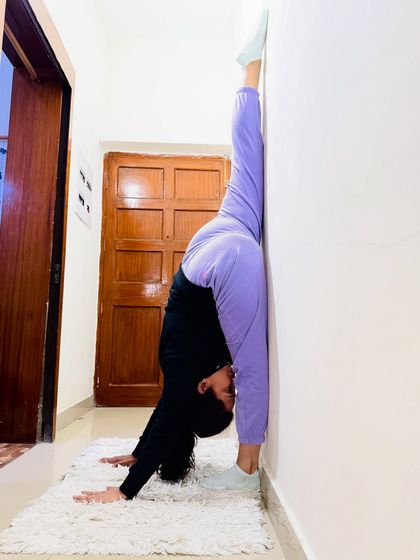 A student holding a perfect Urdhva Prasarita Eka Padasana (Standing Split) against the wall. This shows incredible hamstring flexibility achieved through consistent practice.