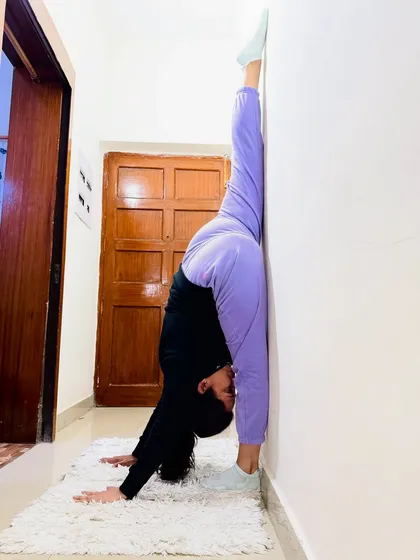 A student holding a perfect Urdhva Prasarita Eka Padasana (Standing Split) against the wall. This shows incredible hamstring flexibility achieved through consistent practice.