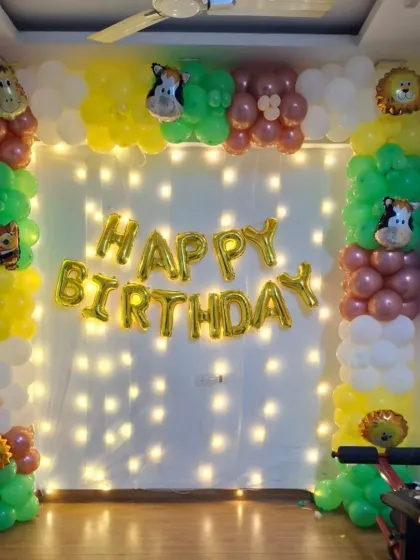 A simple jungle-themed decoration with animal foil balloons, a "Happy Birthday" banner, and a wall of fairy lights.