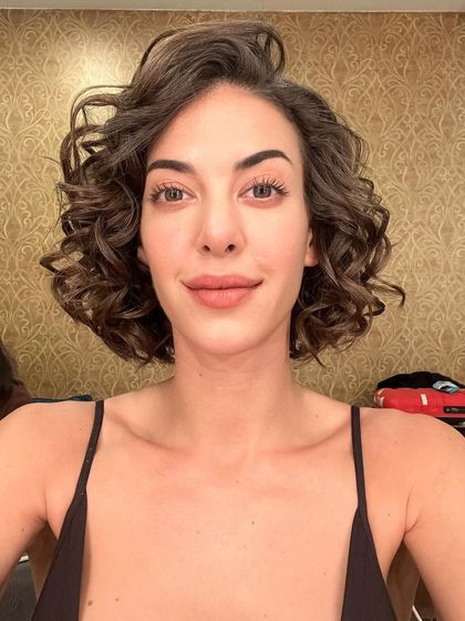 A front-facing view of the natural makeup and curly bob hairstyle for the Realme commercial. The look is clean, fresh, and commercially appealing.