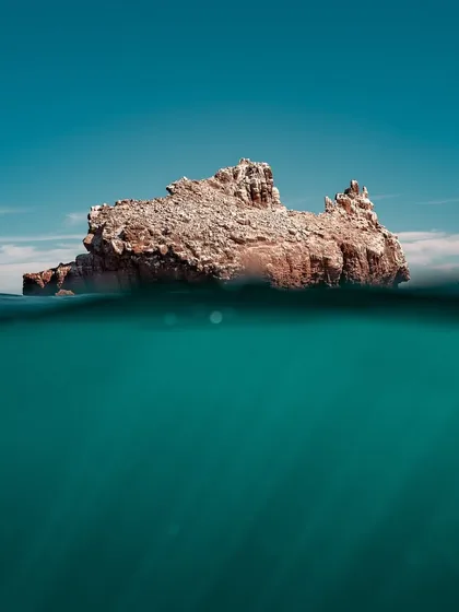 A split-level or over-under photograph showing a rocky island and the underwater world beneath it. This technique offers a unique perspective, telling the story of what's both above and below the surface in a single frame.
