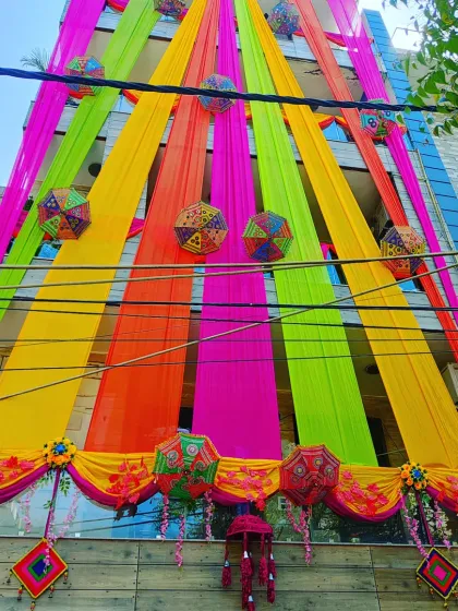 An upward view of the vibrant house decoration, showing how the colourful drapes and umbrellas create a stunning visual against the sky.